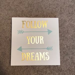 Wall canvas that says “Follow your dreams.”